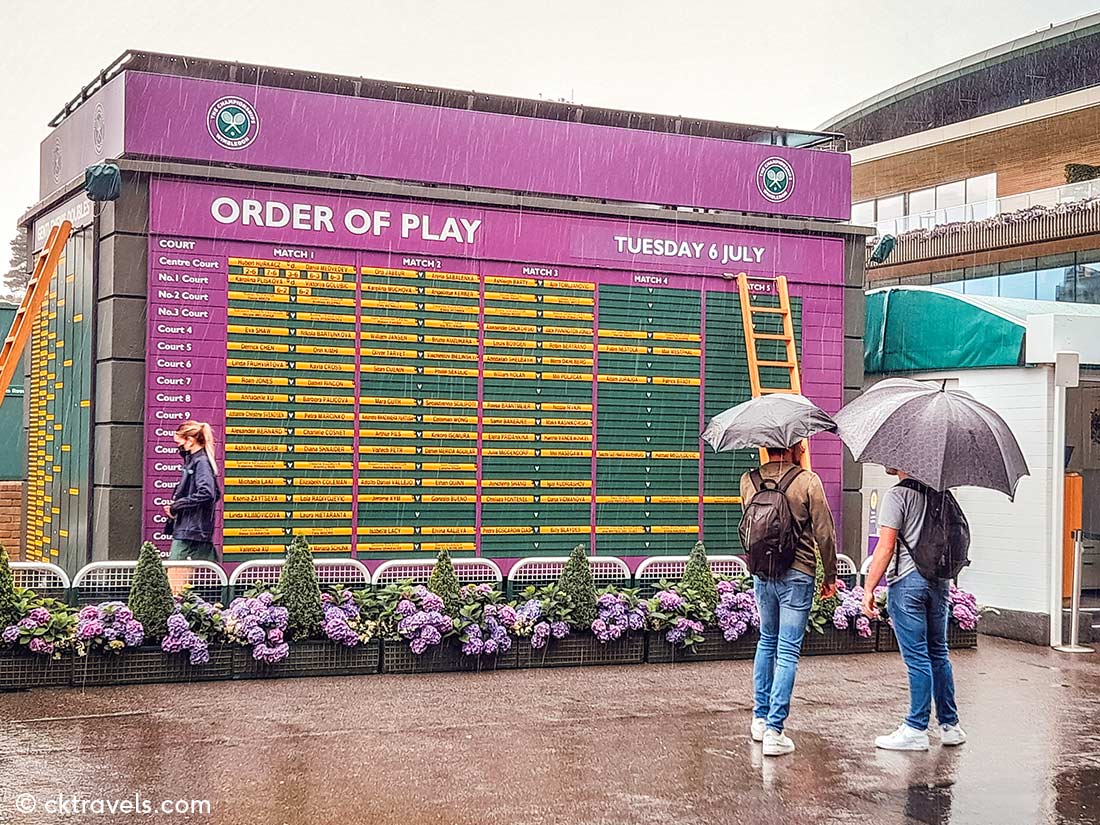 Order of play at Wimbledon tennis in the rain umbrellas. All England Lawn Tennis and Croquet Club. Copyright CK Travels